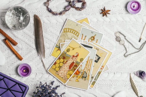 Изображение с дамским Таро на апрель, окруженное различными аксессуарами для гадания, такими как кристаллы, перо, лаванда и украшения.