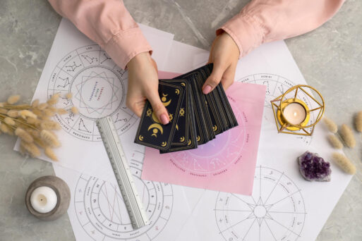 Человек раскладывает карты Таро на столе с астрологическими картами и свечами, таро на выходные.
